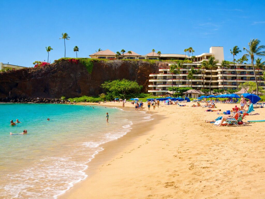 Families swimming and relaxing on Kaanapali Beach in front of a beachfront resort, Maui